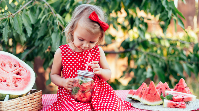 Un niño lindo come sandía jugosa madura en verano. Niño, bebé, merienda de comida saludable para niños. Niña adorable que intenta vender limonada