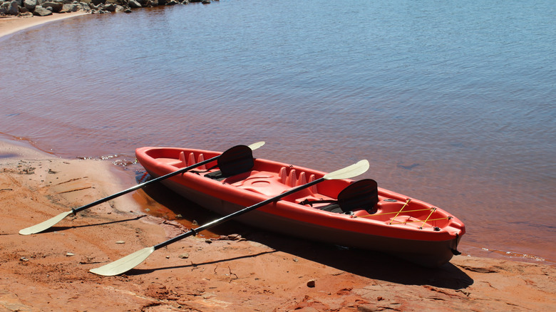 Un kayak rojo en la orilla de arena roja del lago Stanley Draper en Oklahoma City, Oklahoma