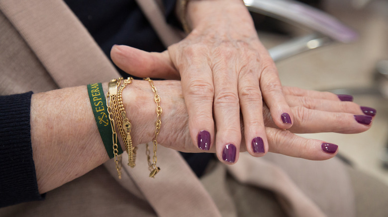 Una mujer con uñas de color morado oscuro.