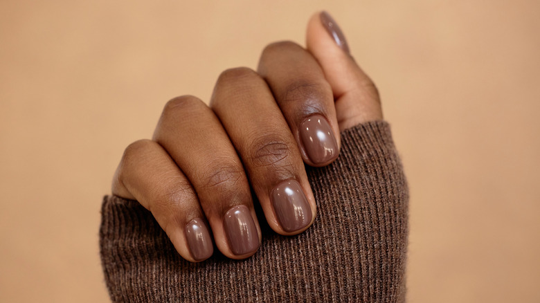 Primer plano de una manicura con esmalte de uñas marrón.