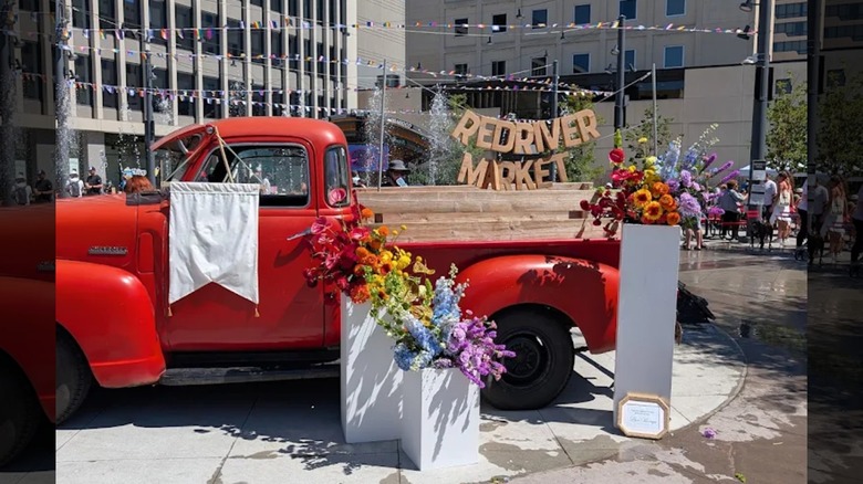 El cartel del Red River Market con un camión rojo y flores