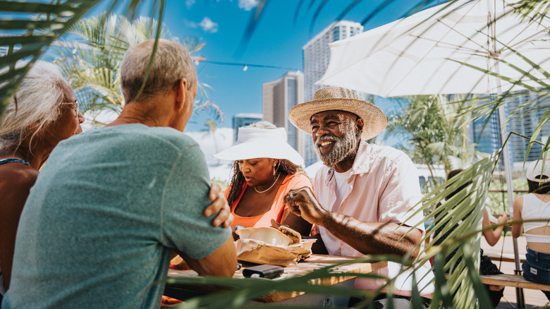 Dos felices parejas de jubilados disfrutando de una comida en un restaurante al aire libre en Honolulu