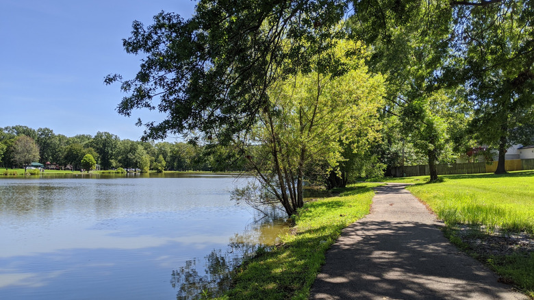 Sendero pavimentado, flanqueado por césped y árboles, junto al lago en Arnold City Park, Missouri