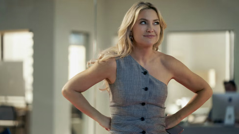 Kate Hudson con un top gris de un solo hombro y un reventón