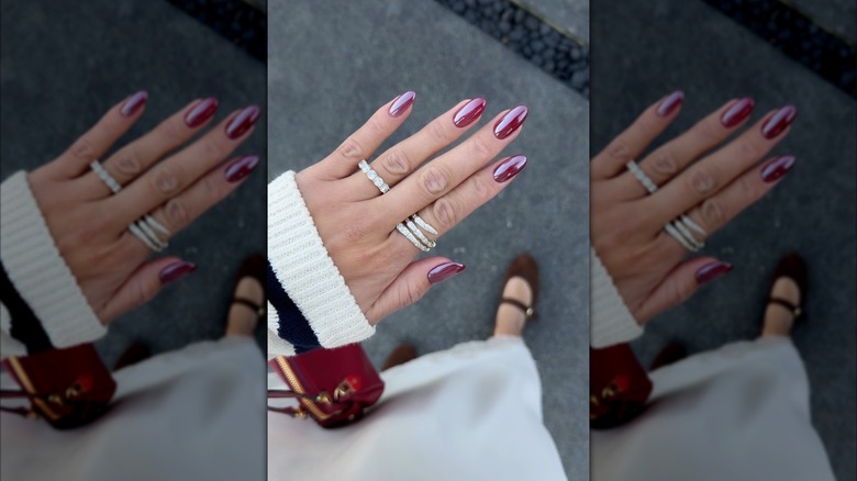 Una mano con uñas cromadas de color burdeos.