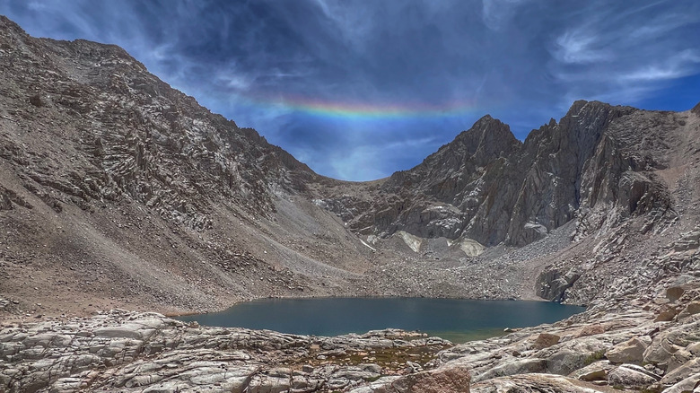 Grava y granito inclinados hacia los lagos de consulta de profundas aguas azul verdosas con un prisma sobre una grieta de montaña