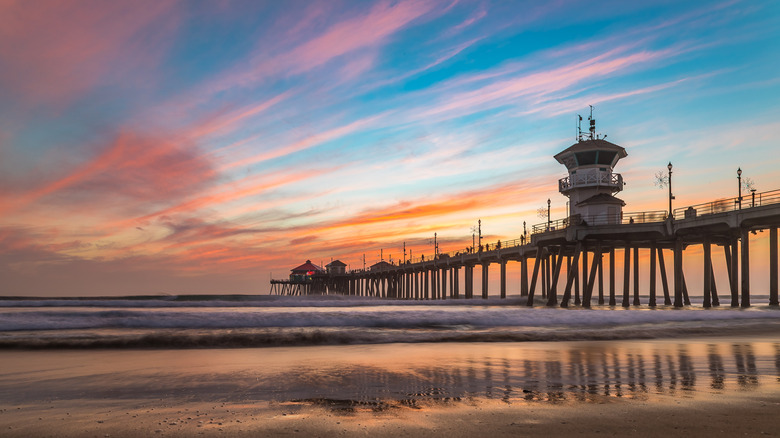 Muelle Huntington que se adentra en el Océano Pacífico con los colores del cielo del atardecer en el horizonte.