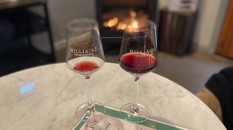 Dos copas de vino tinto en copas junto a una chimenea en Milliaire Winery en el condado de Calaveras.