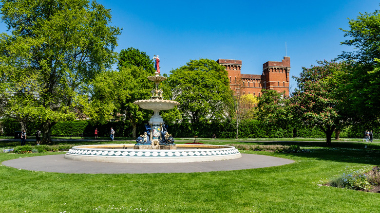 Fuente decorada y edificio histórico de ladrillo rojo en Vivary Park