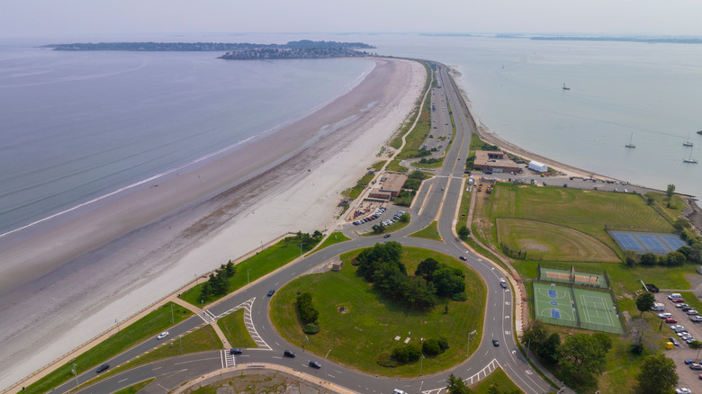 Vista aérea de la larga franja de arena de Nahant Beach junto a la carretera con barcos en el agua, en Massachusetts