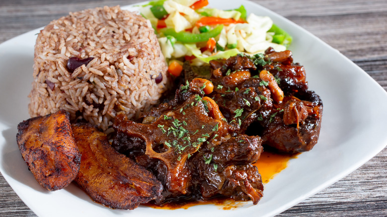 Rabo de toro estofado con arroz y verduras en un plato blanco