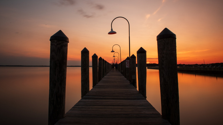 Una puesta de sol de Delaware de color naranja intenso y rojo sobre un muelle en la Bahía de Rehoboth en el Faro, Dewey Beach