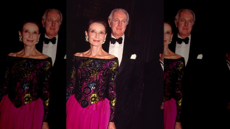Audrey Hepburn con un vestido con hombros descubiertos y un elaborado estampado y el diseñador de moda francés Hubert de Givenchy con un esmoquin en un evento de moda.