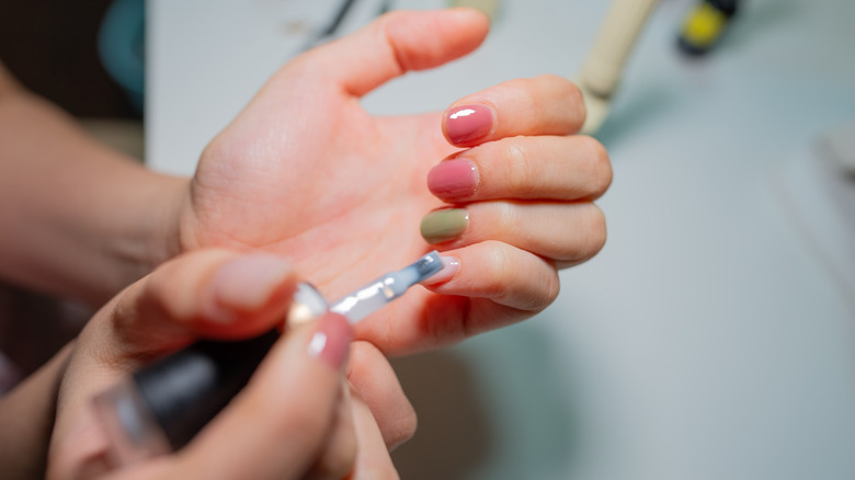 Una persona pintándose diferentes colores de esmalte en gel en las uñas.