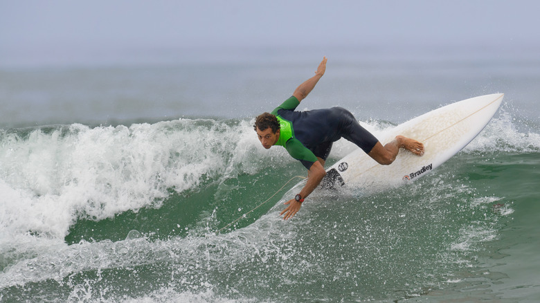 Cerca de un surfista en traje de neopreno montando una ola en Trestles Beach, California.