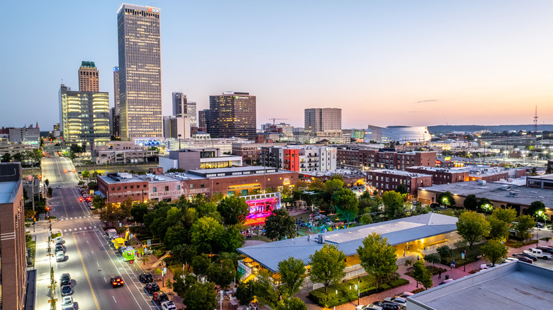 Vista aérea del parque Guthrie Green iluminado para un concierto al aire libre al atardecer con Tulsa, el horizonte de la ciudad de Oklahoma al fondo