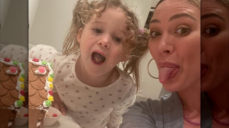 Hilary Duff y su hija Banks sacan la lengua mientras decoran una casa de jengibre en pijama.