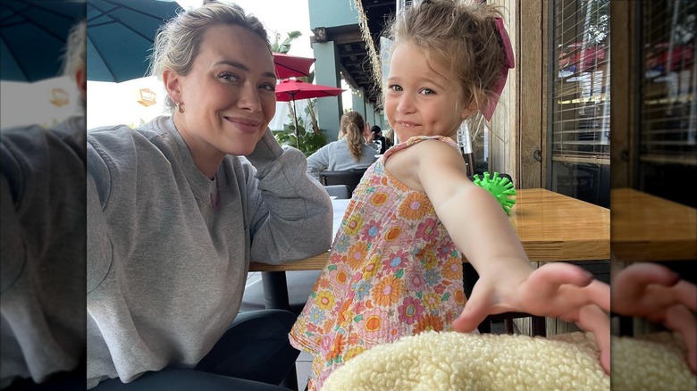Hilary Duff lleva el pelo recogido en un moño desordenado y una sudadera gris mientras está sentada con Banks en un restaurante de sushi.