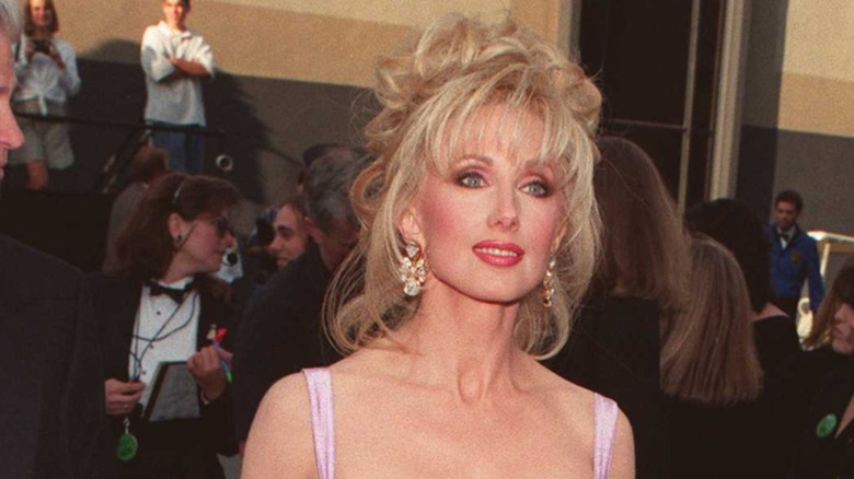 Morgan Fairchild en 1996 en la alfombra roja con un recogido desordenado y un flequillo tenue.