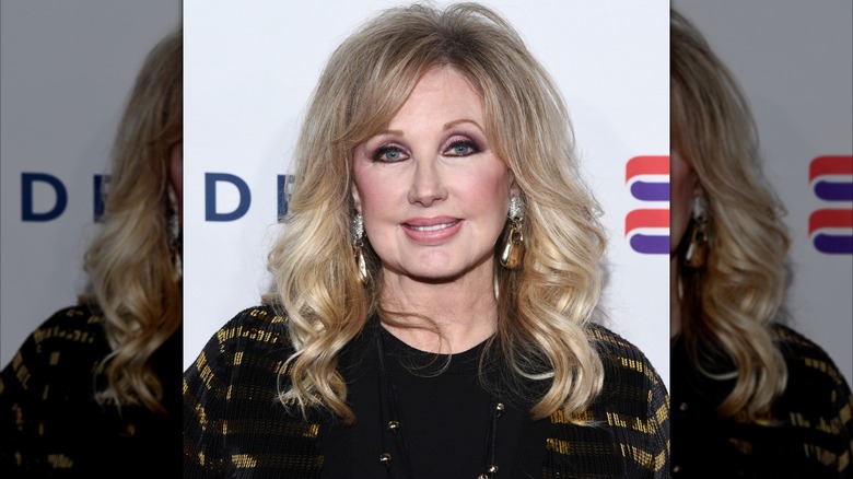 Morgan Fairchild vestida de negro en un evento en 2019 con el cabello suavemente rizado.