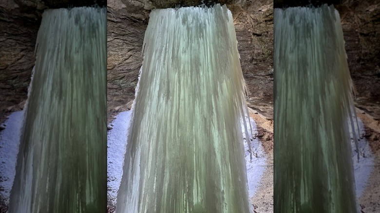 Una cascada de hielo refleja el blanco, el verde y el naranja de su entorno en Boulder Canyon en el Parque Estatal Turkey Run.