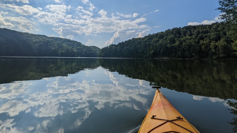 Un kayak flotando en las tranquilas aguas del lago Yatesville en el Parque Estatal Yatesville Lake, Kentucky, con el paisaje reflejado en el agua
