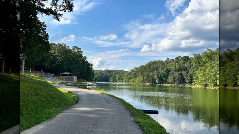 Un camino pavimentado junto al lago Yatesville en el Parque Estatal Yatesville Lake, Kentucky, rodeado de vegetación bajo un cielo parcialmente nublado