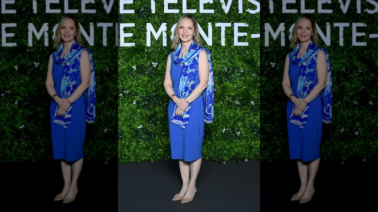 Melissa Sue Anderson sonríe luciendo un vestido midi azul cobalto y una bufanda azul cobalto y celeste