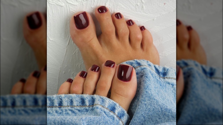 Una pedicura con esmalte de uñas burdeos oscuro.