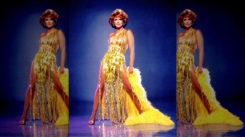 Ann-Margret lleva un vestido de lentejuelas doradas y una capa de plumas diseñada por Bob Mackie en 1980.