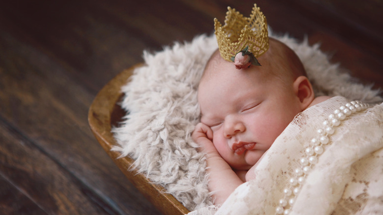 Niña durmiendo con una tiara y una manta de perlas
