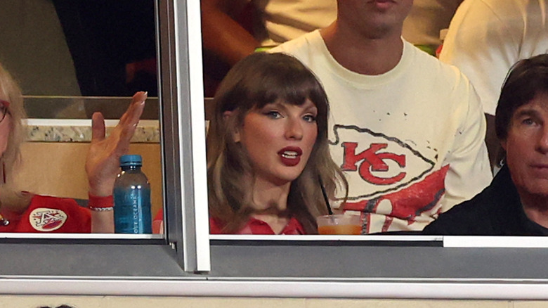 Taylor Swift con el pelo con rizos claros sentada junto a Tom Cruise en el partido de los Kansas City Chiefs contra los Denver Broncos