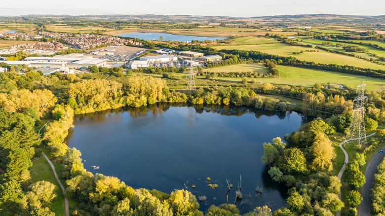 Un pequeño lago en el campo, a las afueras de Leighton Buzzard, rodeado de árboles y campos rurales.