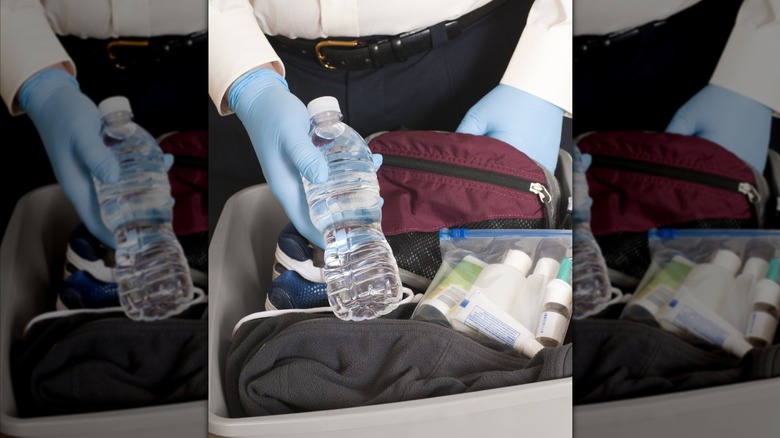 Seguridad sosteniendo una botella de agua del equipaje de alguien.