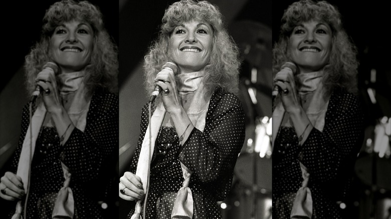 Stella Parton fotografiada en 1980 con una bufanda y un vestido de lunares mientras cantaba