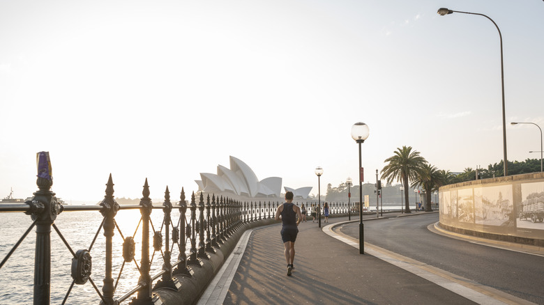 Un corredor corriendo hacia la Ópera de Sydney a primera hora de la mañana