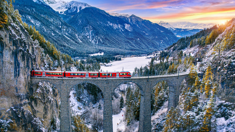 Un tren rojo cruzó un puente histórico sobre un acueducto en los Alpes suizos