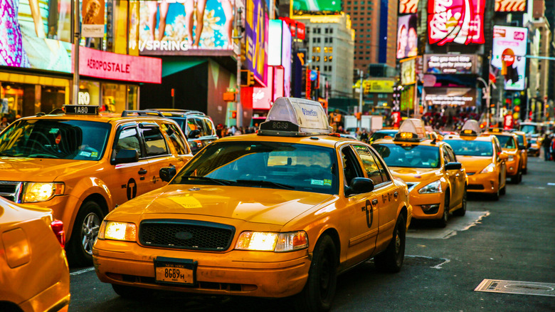 Línea de taxis amarillos en Times Square, Nueva York, vallas publicitarias brillantes detrás de ellos