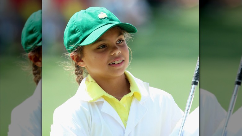 Sam Woods lleva el pelo recogido en trenzas debajo de una gorra verde de Masters con una camiseta de color amarillo brillante mientras asiste al Torneo de Masters de 2015 en Georgia.