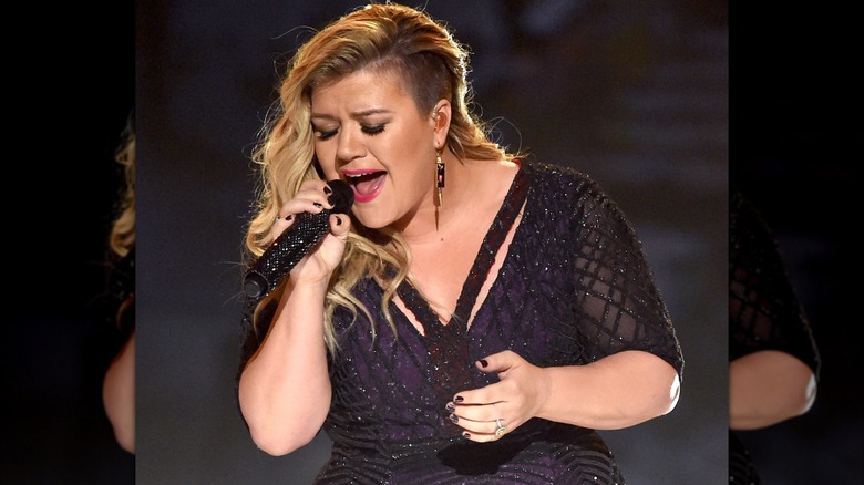 Kelly Clarkson con un corte afeitado actuando en el escenario en 2015