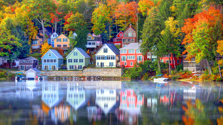 Casas coloridas ubicadas en el lago Winnipesaukee, bordeadas de árboles rojos, naranjas y amarillos.