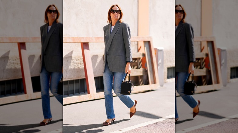 Una mujer vestida con jeans rectos y una chaqueta de tweed.