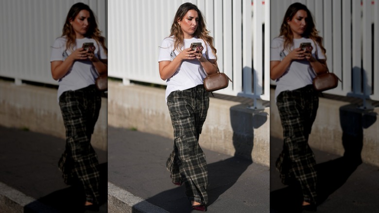 Una mujer vestida con pantalones a cuadros y una camiseta blanca.