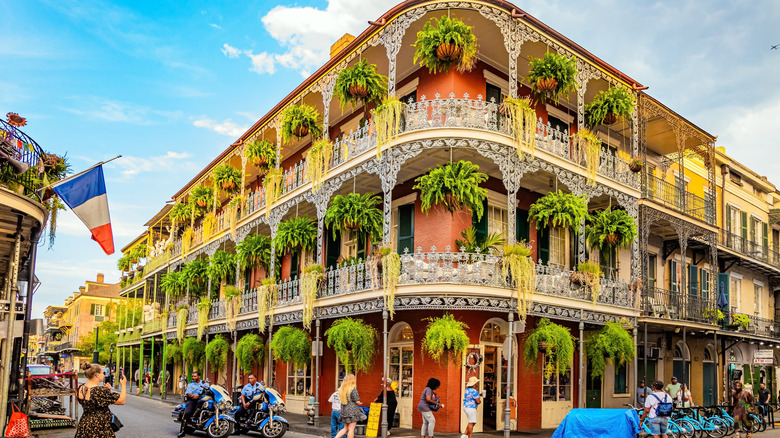 Edificio histórico de ladrillo rojo de tres pisos ubicado en el Barrio Francés de Nueva Orleans con exuberantes maceteros colgantes y balcones de hierro forjado