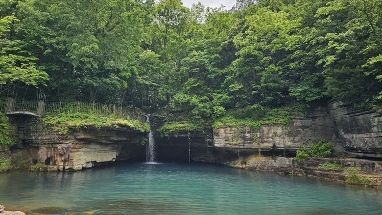 Acantilados de piedra caliza y un charco de agua azul, rodeado de vegetación en el Parque Natural Dogwood Canyon, Missouri