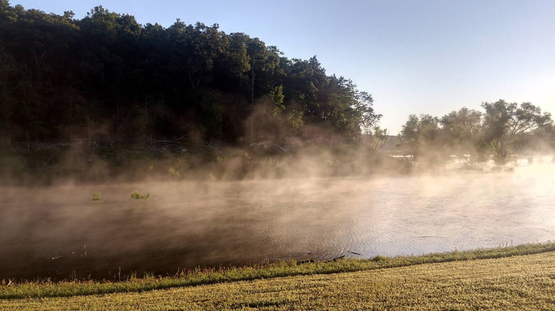 Niebla saliendo de un lago con árboles en el fondo en Beaver Creek Park, Missouri