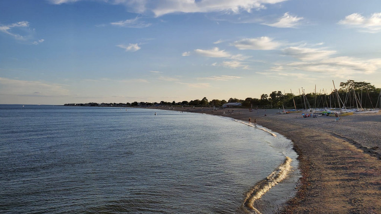 Las tranquilas aguas de Jennings Beach al atardecer, con barcos y gente en la orilla