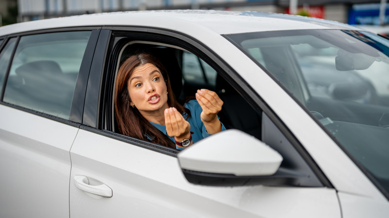 Mujer haciendo gestos agresivos con las manos desde su coche