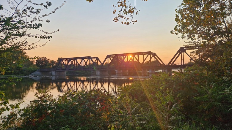 Vista del río y del puente ferroviario desde un sendero que recorre el río Raisin en Monroe, MI