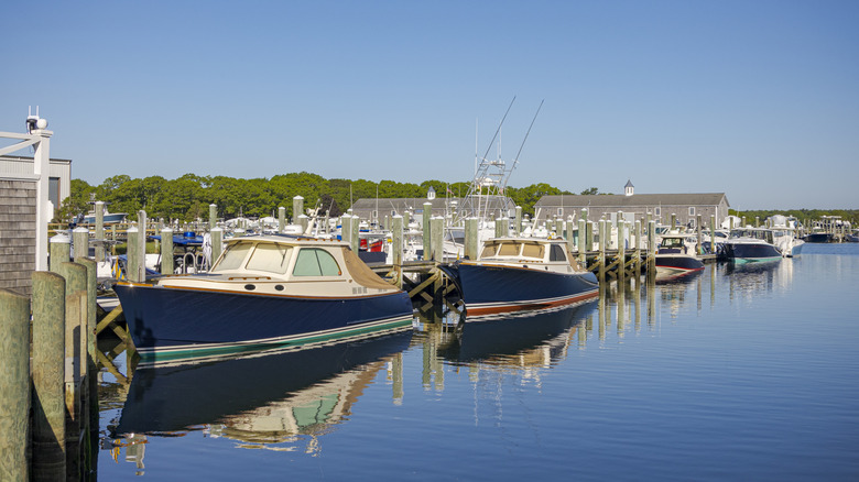 Pequeñas lanchas atracadas en muelles de madera en un tranquilo y soleado puerto deportivo costero en Barnstable, Massachusetts